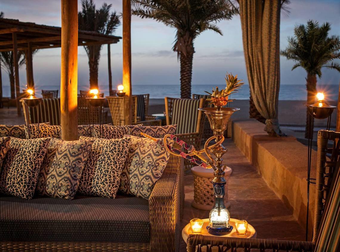 Loungebereich im St. Regis Saadiyat Island Resort mit Blick auf den Ozean und Palmen.