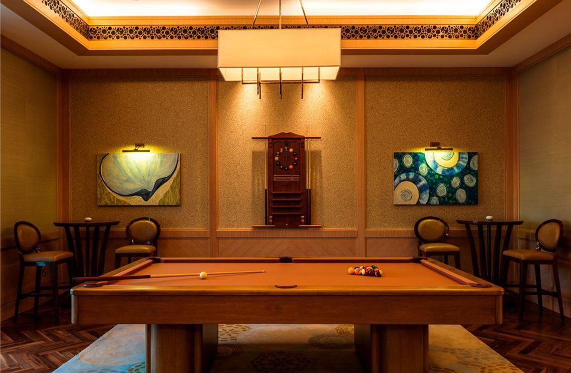 Pooltisch im Spielzimmer des St. Regis Saadiyat Island Resort mit zwei Kunstwerken an der Wand und runden Stühlen