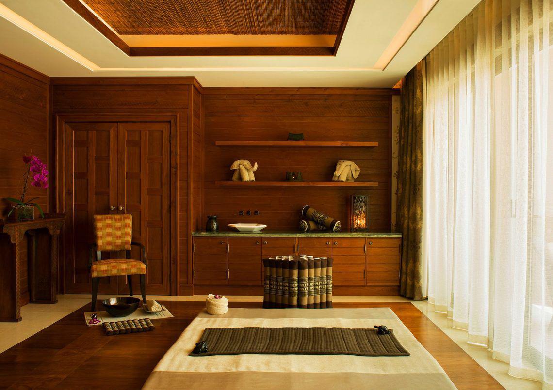 Innenansicht eines Massageraums im St. Regis Saadiyat Island Resort mit Holzmöbeln und Dekogegenständen.