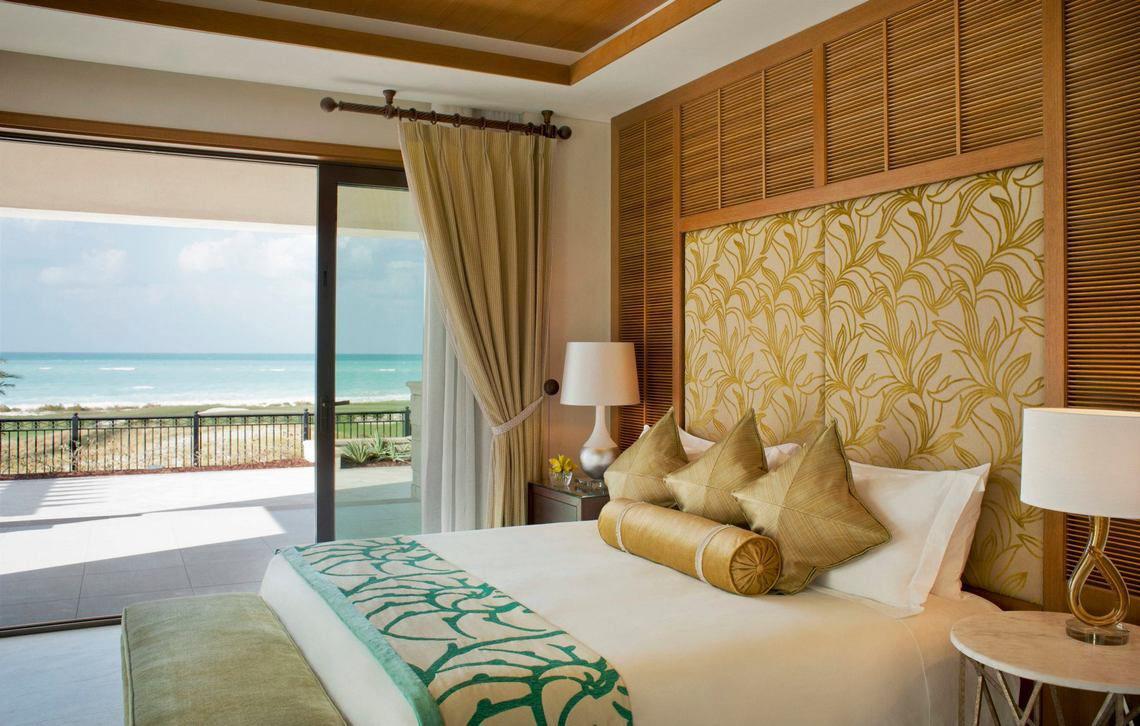 Hotelzimmer mit Meerblick im St. Regis Saadiyat Island Resort mit Bett, Kissen und Lampen