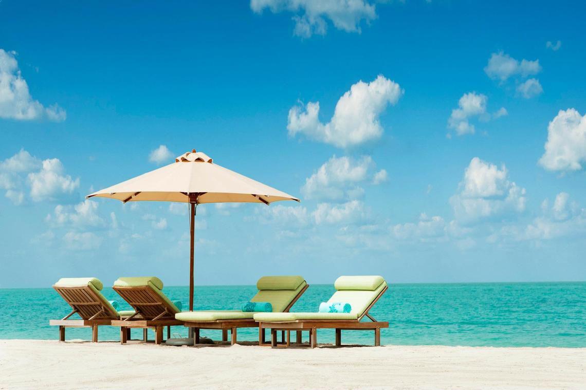 Strand mit Liegen und Sonnenschirm am The St. Regis Saadiyat Island Resort