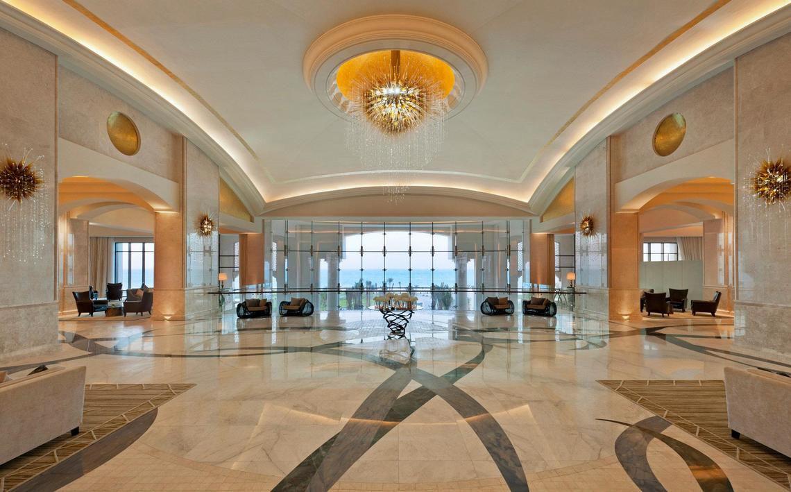 Lobby des St. Regis Saadiyat Island Resort mit großem Kronleuchter und Blick aufs Meer.