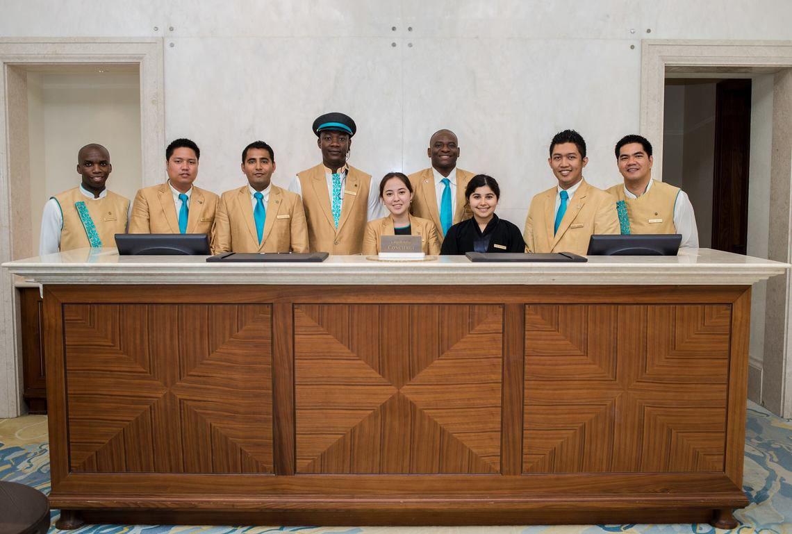 Empfangsteam des St. Regis Saadiyat Island Resorts vor dem Empfangstresen