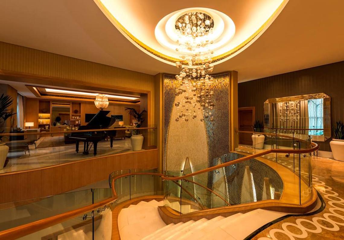 Empfangsbereich im St. Regis Saadiyat Island Resort mit einer Wendeltreppe und einem großen Kristallleuchter.