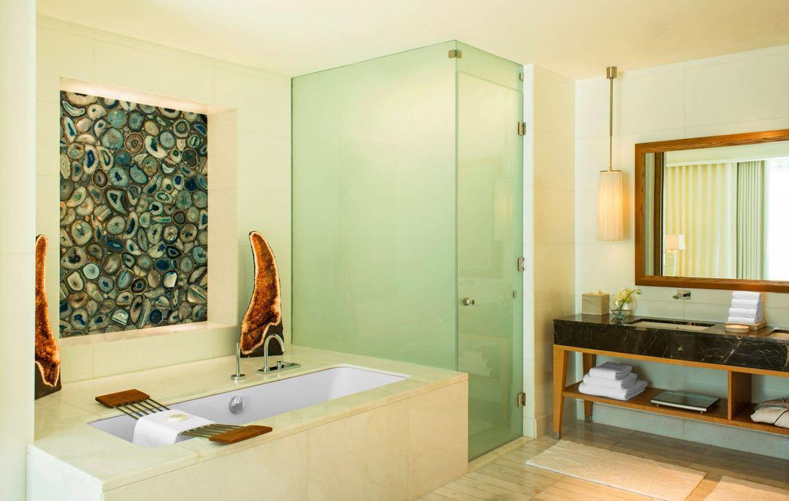 Das Badezimmer im St. Regis Saadiyat Island Resort mit Badewanne, Glasdusche und Marmorwaschtisch.