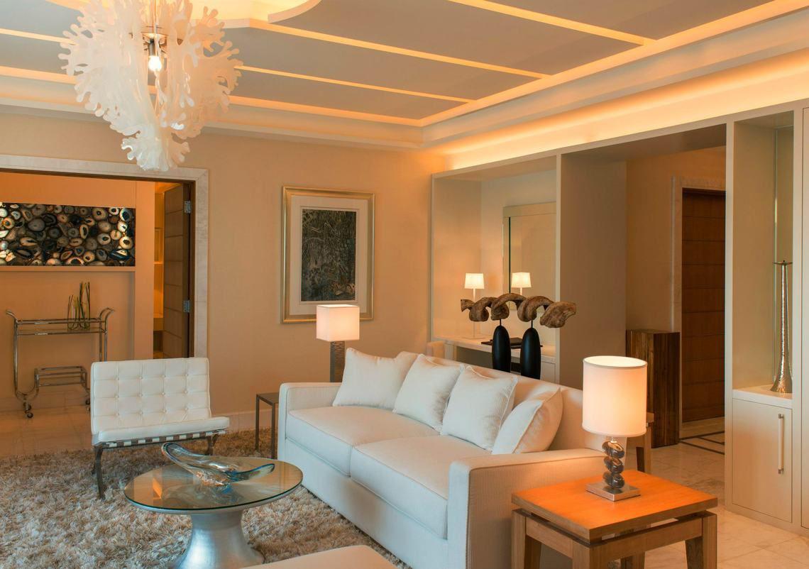 Wohnzimmer im St. Regis Saadiyat Island Resort mit weißer Couch, Lampen und Teppich.