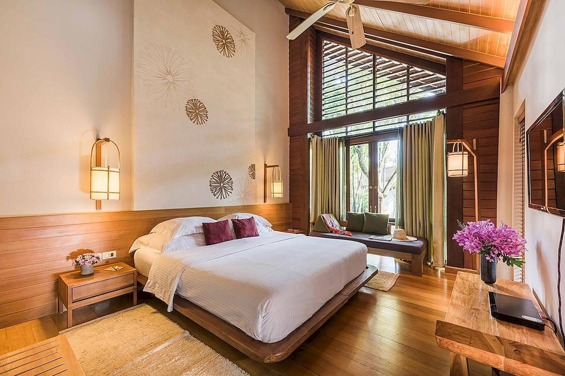 Schlafzimmer im Tubkaak Krabi Boutique Resort mit einem großen Bett, Wandlampen und einer Aussicht auf den Garten.