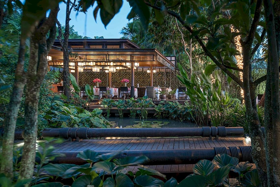 Außenbereich des Tubkaak Krabi Boutique Resorts mit abendlicher Beleuchtung und Tischen im Freien.