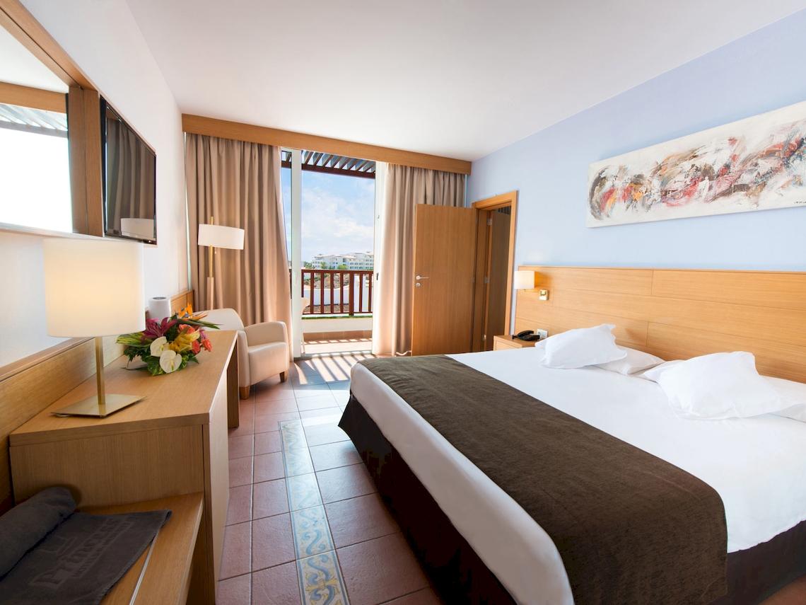 Innenansicht eines Hotelzimmers im Fuerteventura Princess mit einem Bett, einem Balkon und einer modernen Einrichtung.