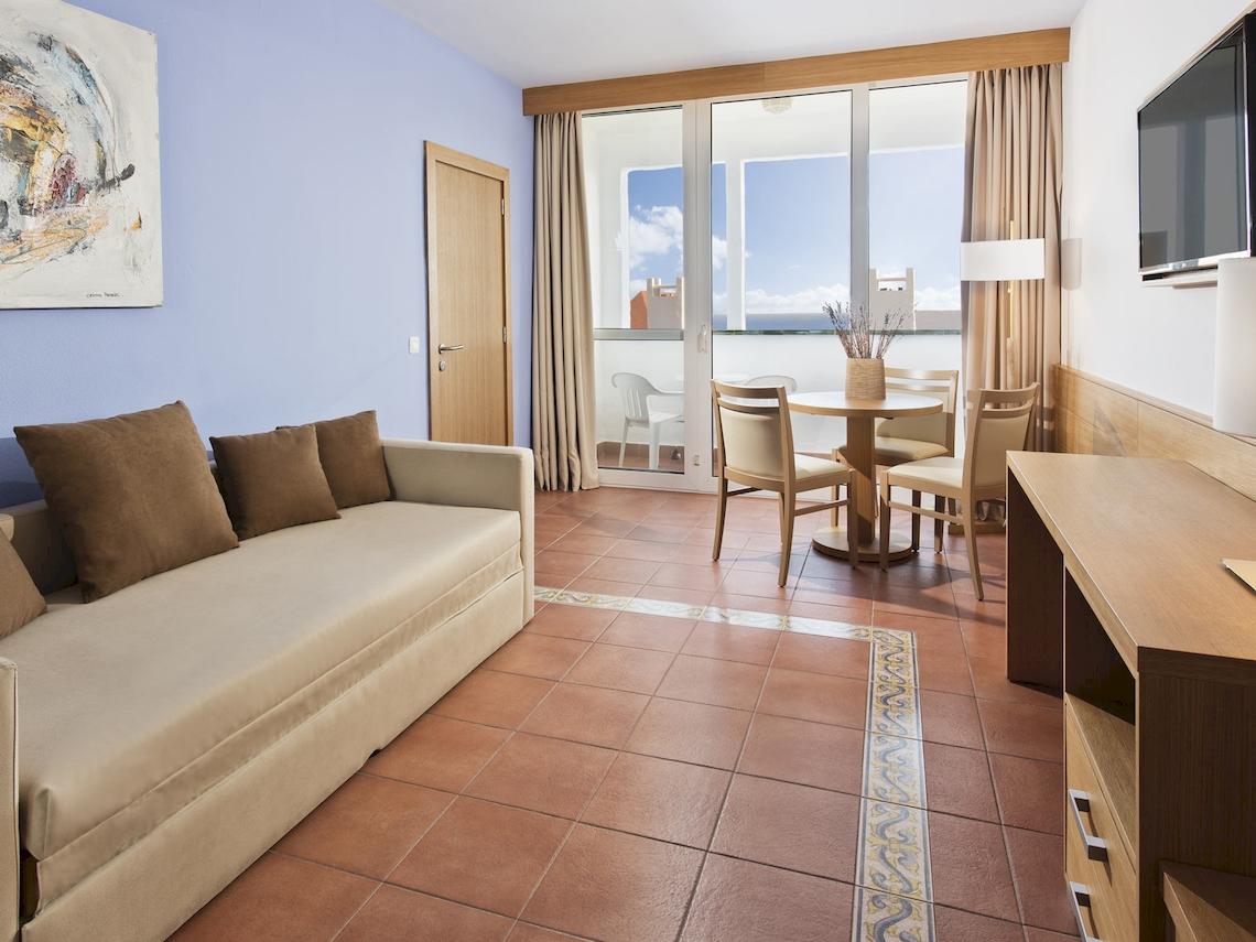 Wohnbereich im Fuerteventura Princess Hotel mit Sofa, Esstisch und Meerblick.