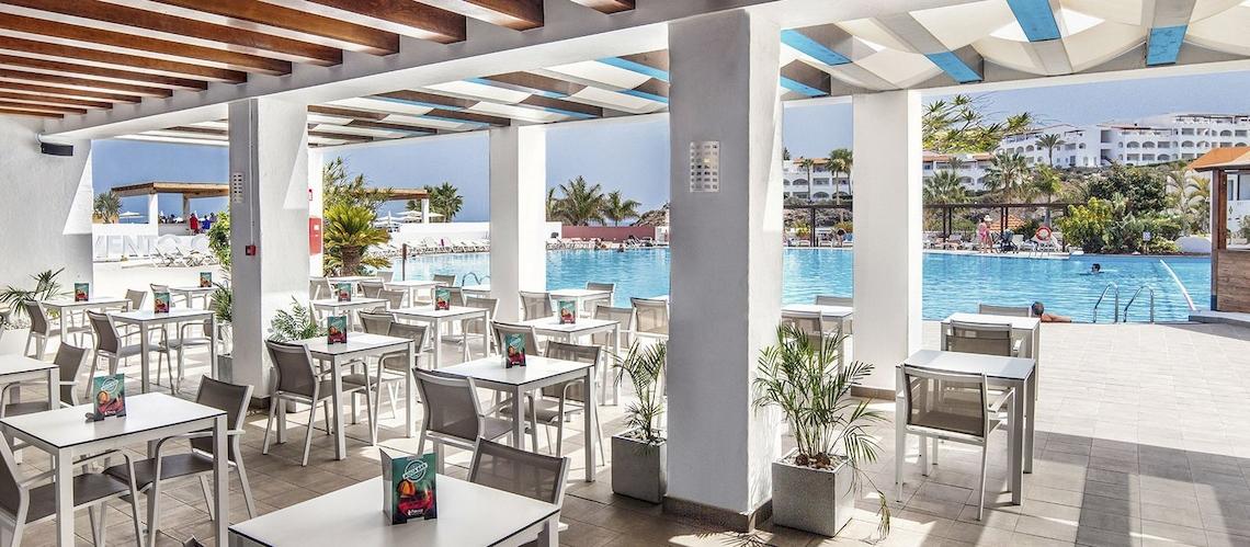 Restaurantbereich mit Tischen und Stühlen neben einem Swimmingpool im Fuerteventura Princess Hotel.