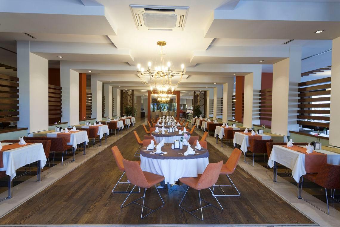 Innenbereich des Seher Sun Palace Resort & Spa Restaurants mit langen Tischreihen und einem Kronleuchter.