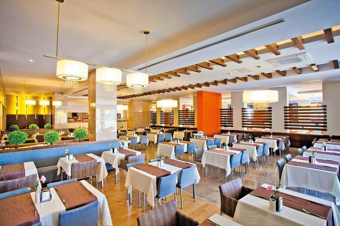 Restaurant des Seher Sun Palace Resort & Spa mit gedeckten Tischen, modernen Kronleuchtern und blauen Stühlen.