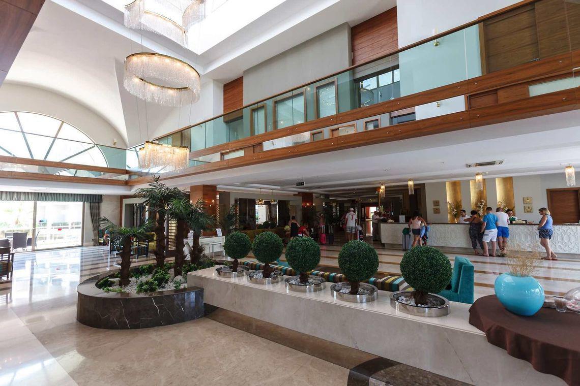 Lobby des Seher Sun Palace Resort mit Rezeption und geformten Büschen