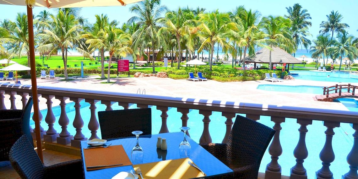 Aussicht vom Balkon des Crowne Plaza Resort Salalah auf den Swimmingpool und die Palmen