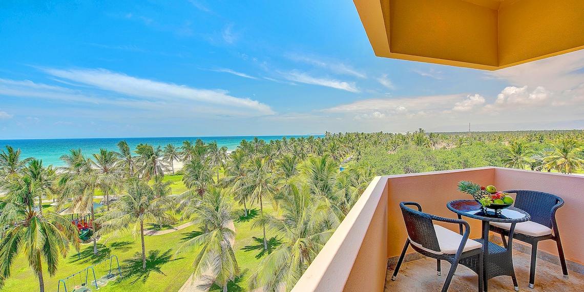 Aussicht vom Balkon des Crowne Plaza Resort Salalah mit Blick auf den Ozean und Palmen.