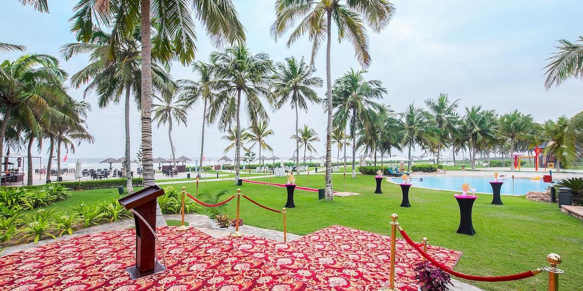 Außenbereich des Crowne Plaza Resort Salalah mit rotem Teppich, roten Seilen und Palmen.