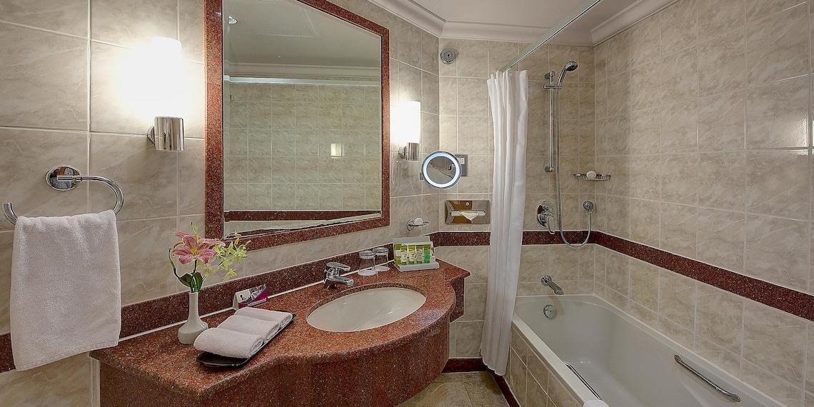Badezimmer im Crowne Plaza Resort Salalah mit Badewanne, Spiegel und Waschbecken.
