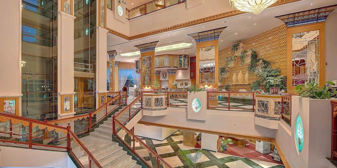 Innenansicht der Lobby im Crowne Plaza Resort Salalah mit Treppen, Pflanzen und kunstvollen Wanddekorationen.