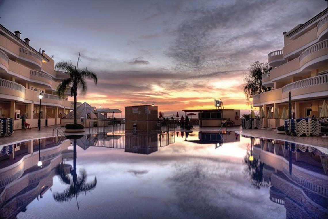 Abendlicher Sonnenuntergang im Bahia Flamingo Hotel mit Pool und Gebäuden im Hintergrund.