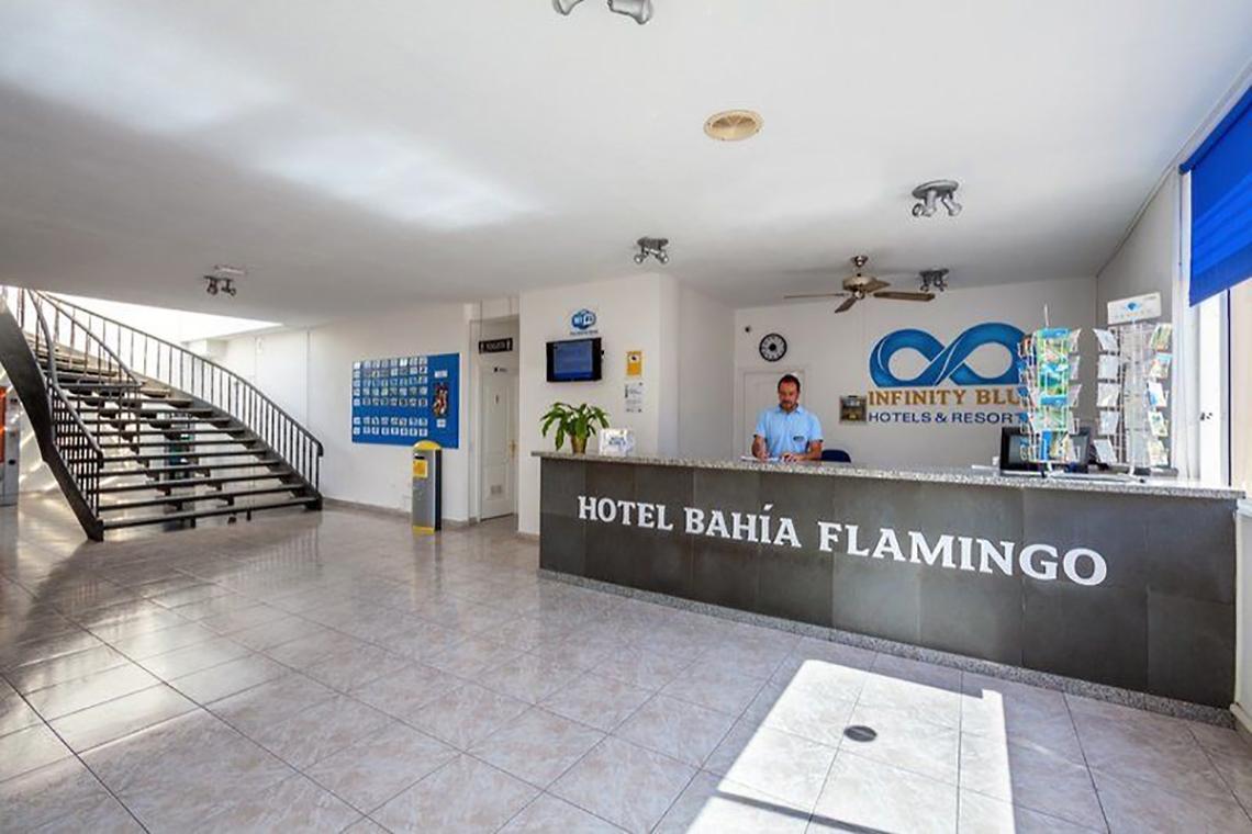 Rezeption des Hotel Bahía Flamingo mit einem Mitarbeiter, der hinter dem Schreibtisch sitzt.