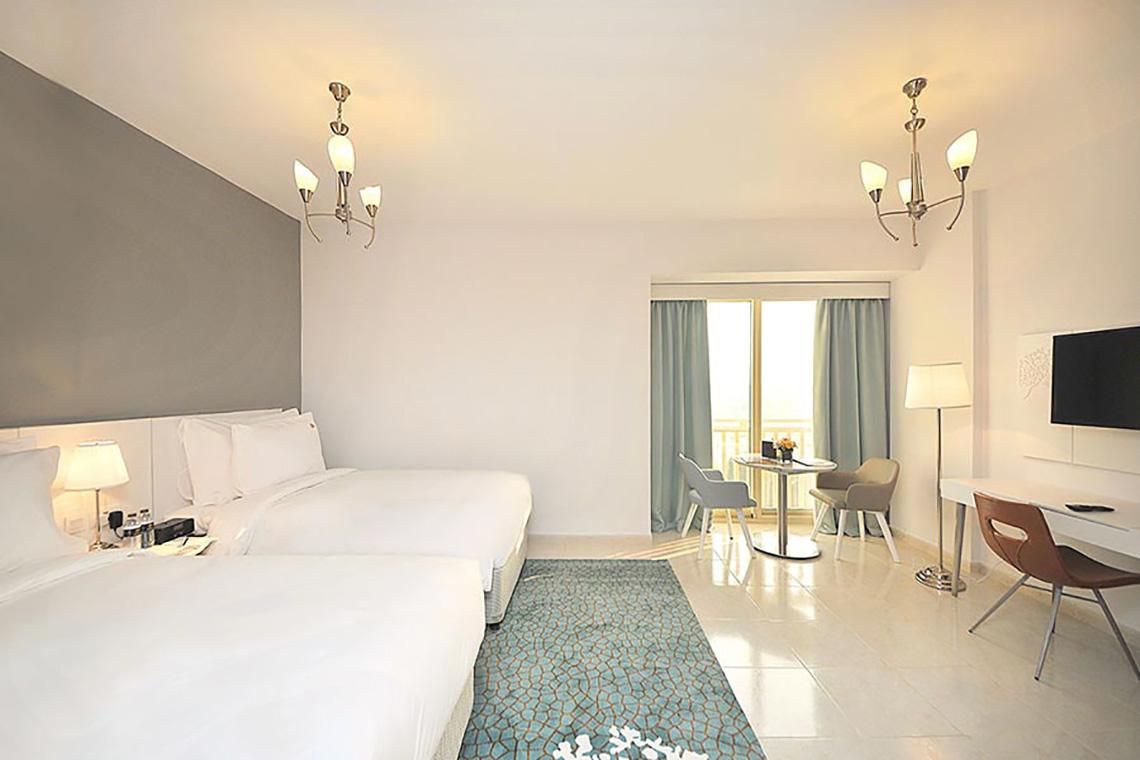 Jannah Hotels Resorts & Villas Zimmer mit zwei Betten, Schreibtisch und Balkon