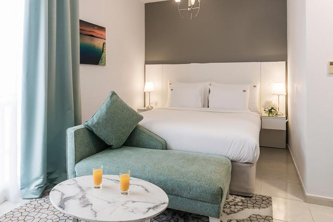 Schlafzimmer im Jannah Hotels Resorts & Villas mit Bett, Kissen, Nachttischen und Gemälde an der Wand.