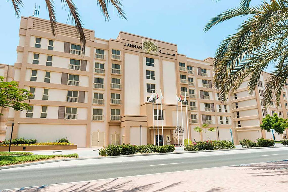 Hauptgebäude von Jannah Hotels Resorts & Villas mit mehreren Flaggen und Palmen
