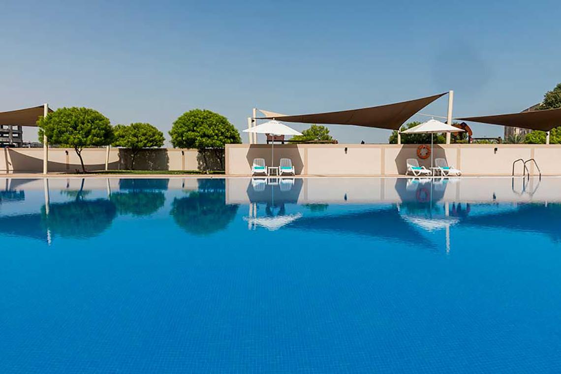 Außenbereich des Jannah Hotels Resorts & Villas mit einem großen Swimmingpool und Sonnenschirmen.