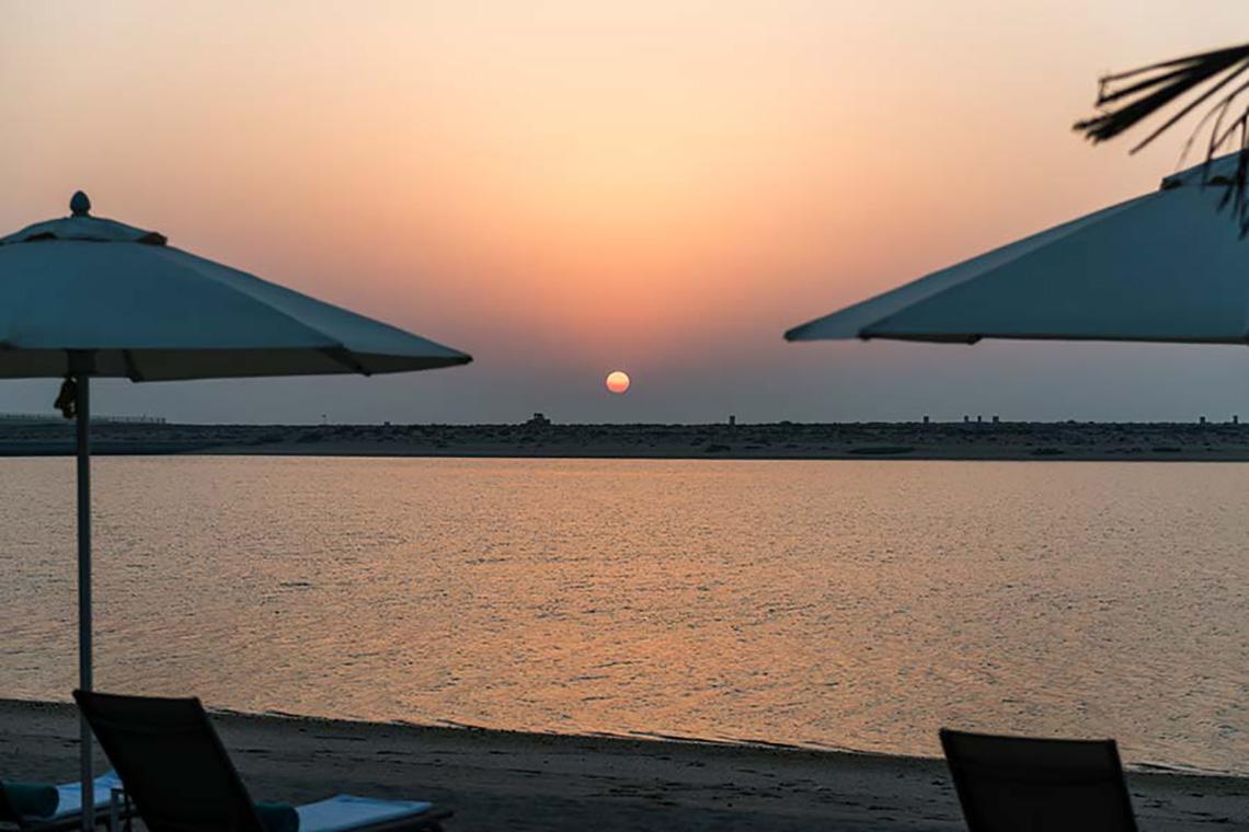 Sonnenuntergang am Strand mit Sonnenschirmen und Strandliegen