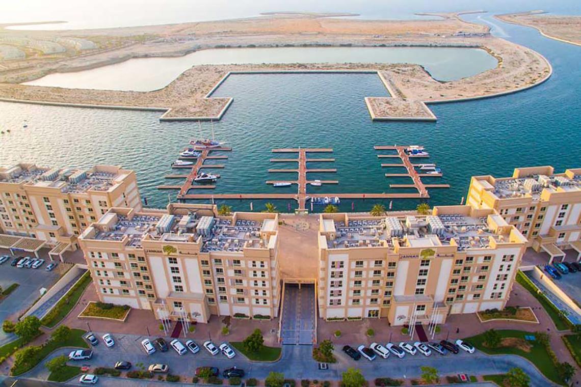 Luftaufnahme des Jannah Hotels Resorts & Villas mit angeschlossener Marina und vielen Autos auf dem Parkplatz.