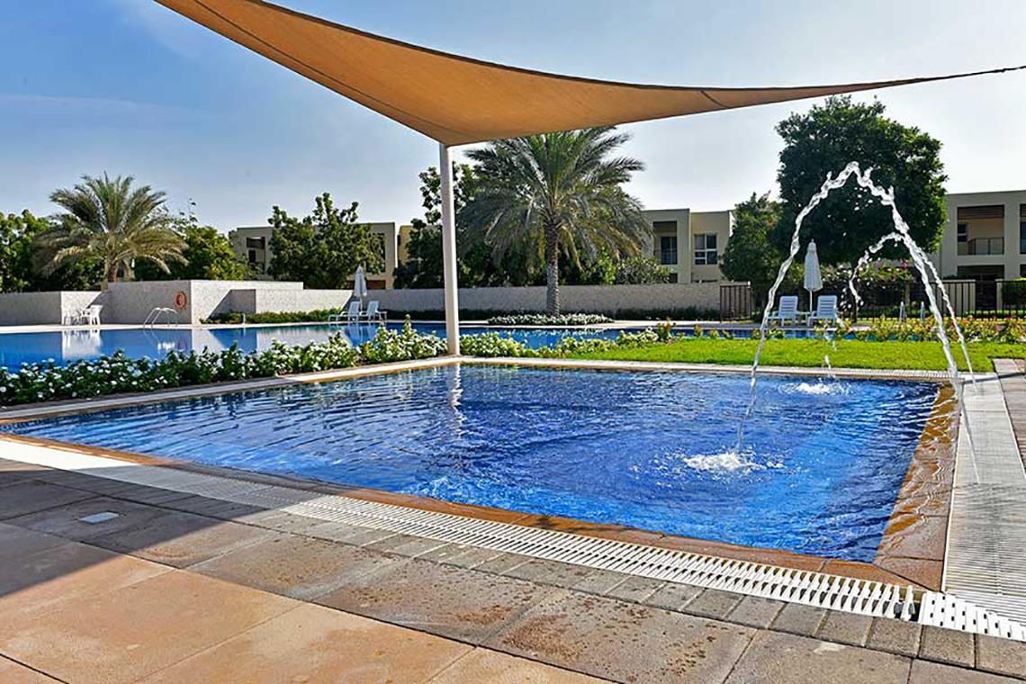 Außenpool im Jannah Hotels Resorts & Villas mit Sonnenschirm und Wasserfontäne.