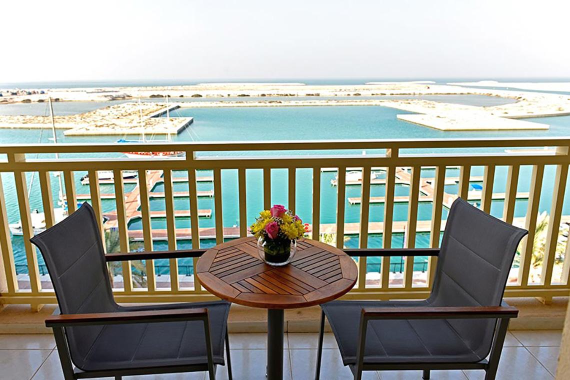 Ein Balkon mit Blick auf das Meer und eine Marina im Jannah Hotels Resorts & Villas.