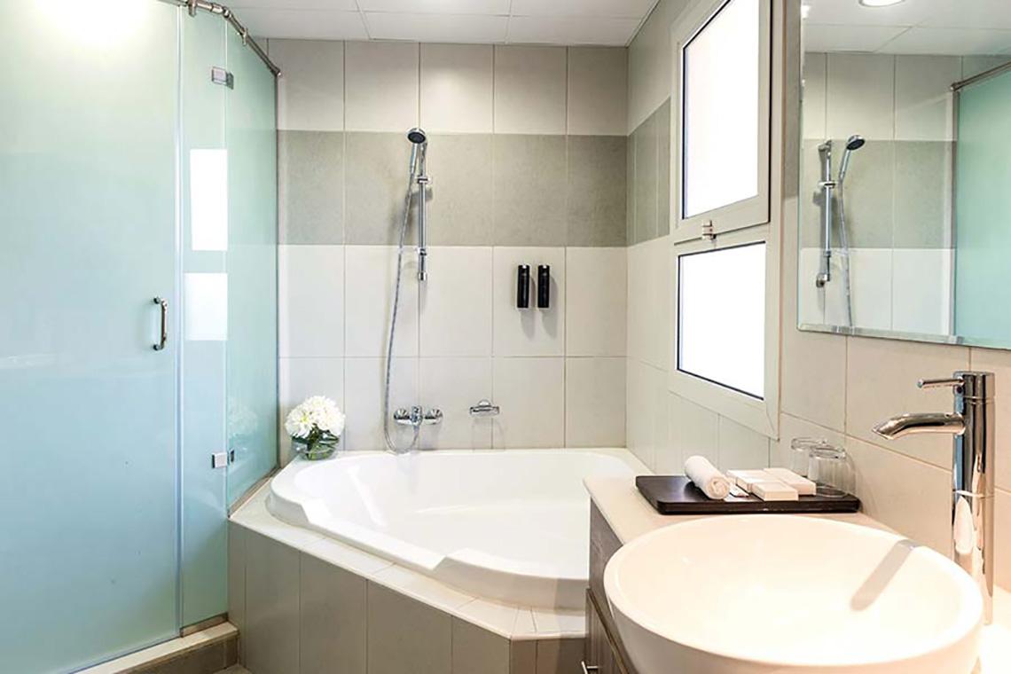 Badezimmer mit Badewanne und Dusche in einem Jannah Hotel.