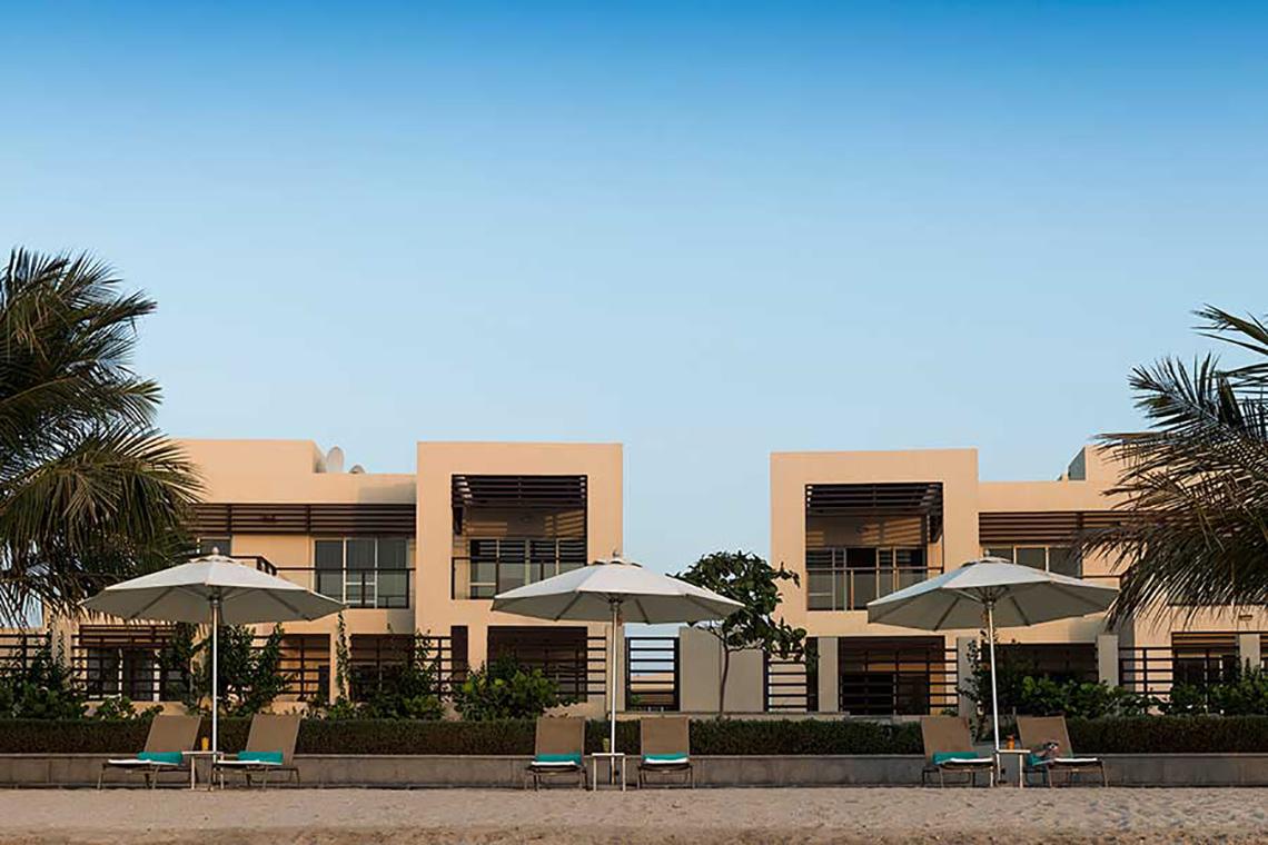 Strand mit Sonnenschirmen und Liegestühlen vor Jannah Hotels Resorts & Villas
