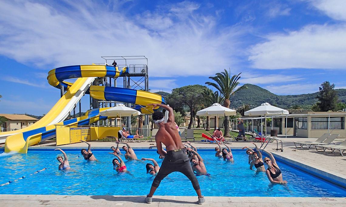 Gruppe macht im Pool Workout mit Wasserrutsche im Hintergrund
