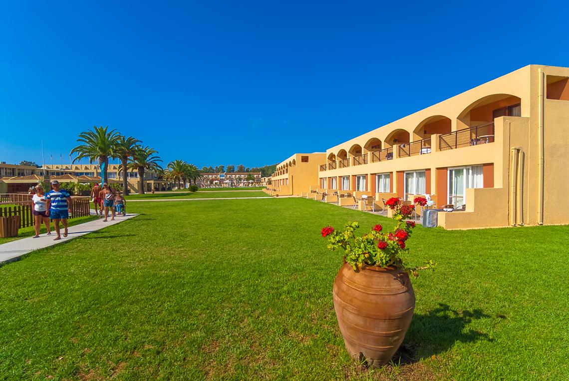 Außenbereich des Messonghi Beach Holiday Resorts mit gepflegtem Rasen und gelben Gebäuden