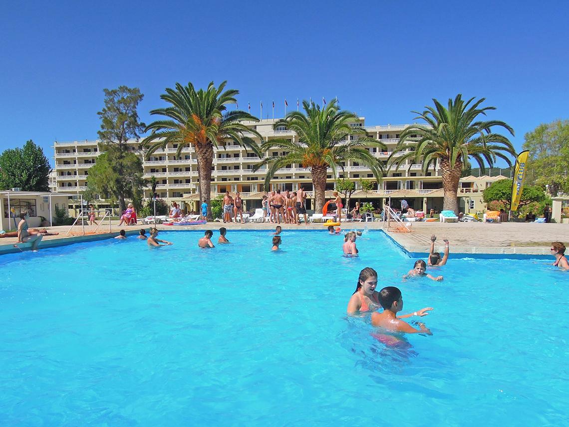 Messonghi Beach Holiday Resort Poolszene mit vielen Schwimmern und Palmen im Hintergrund.