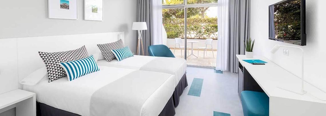 Doppelzimmer im Bluesea Interpalace mit zwei Betten, weißem Dekor und einem Balkon.
