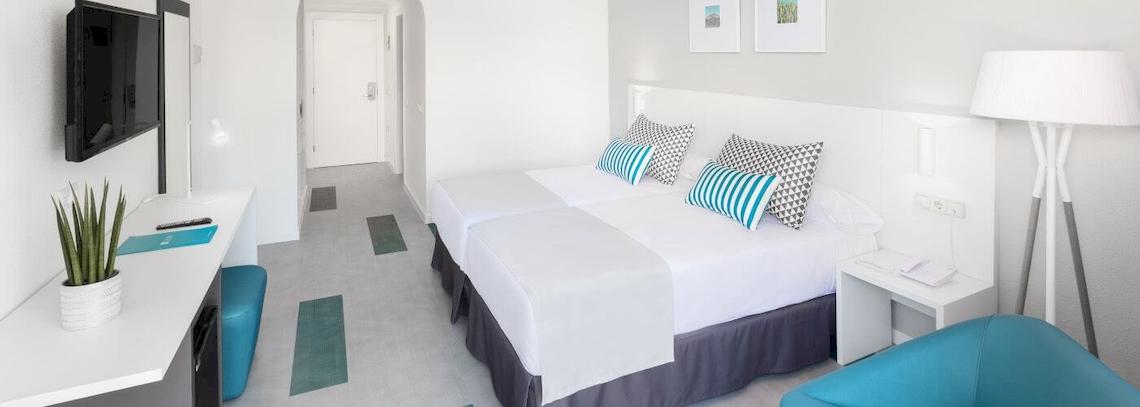 Hotelzimmer im Bluesea Interpalace mit zwei Betten, Fernseher, Schreibtisch und moderner Einrichtung.