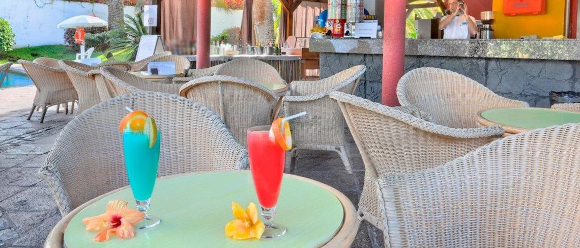 Terrasse des Bluesea Interpalace Hotels mit Tisch, Cocktails und Sonnenschirm.