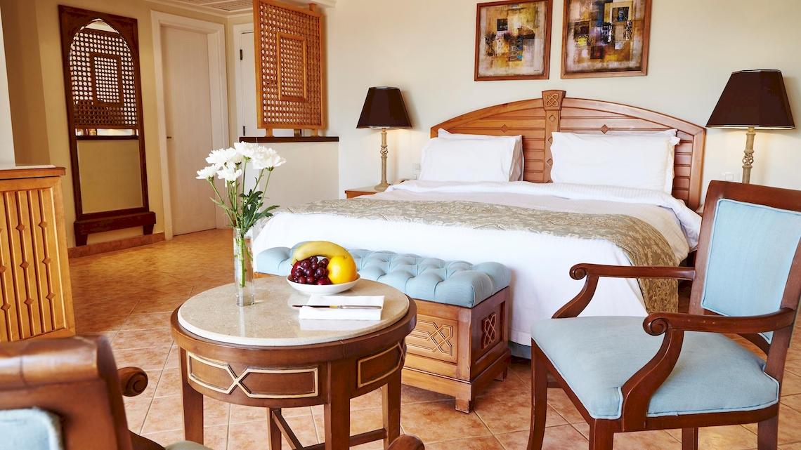 Hotelzimmer im Kempinski Hotel Soma Bay mit großem Bett, Obstschale, Blumenvase und Dekor.