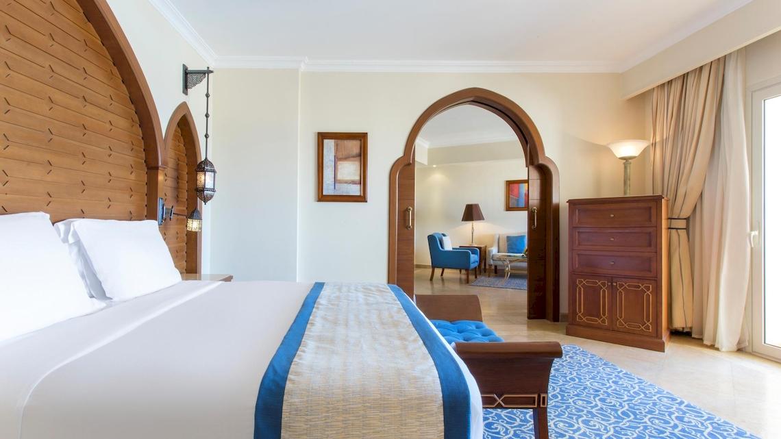 Schlafzimmer im Kempinski Hotel Soma Bay mit Doppelbett, Kissen und dekorativen Elementen.