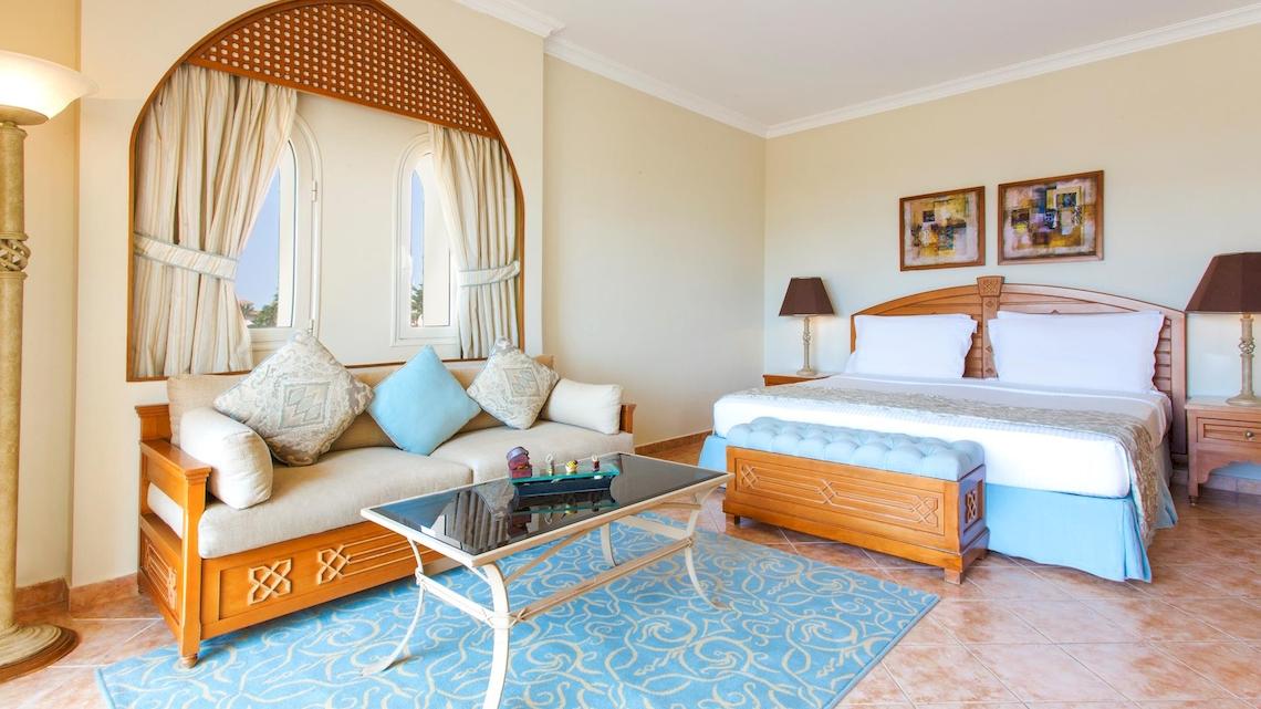 Innenansicht eines Zimmers im Kempinski Hotel Soma Bay mit Bett, Sofa und Tisch.