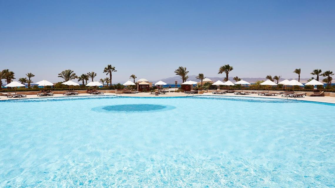 Außenpool des Kempinski Hotels Soma Bay mit vielen Sonnenliegen und Sonnenschirmen.