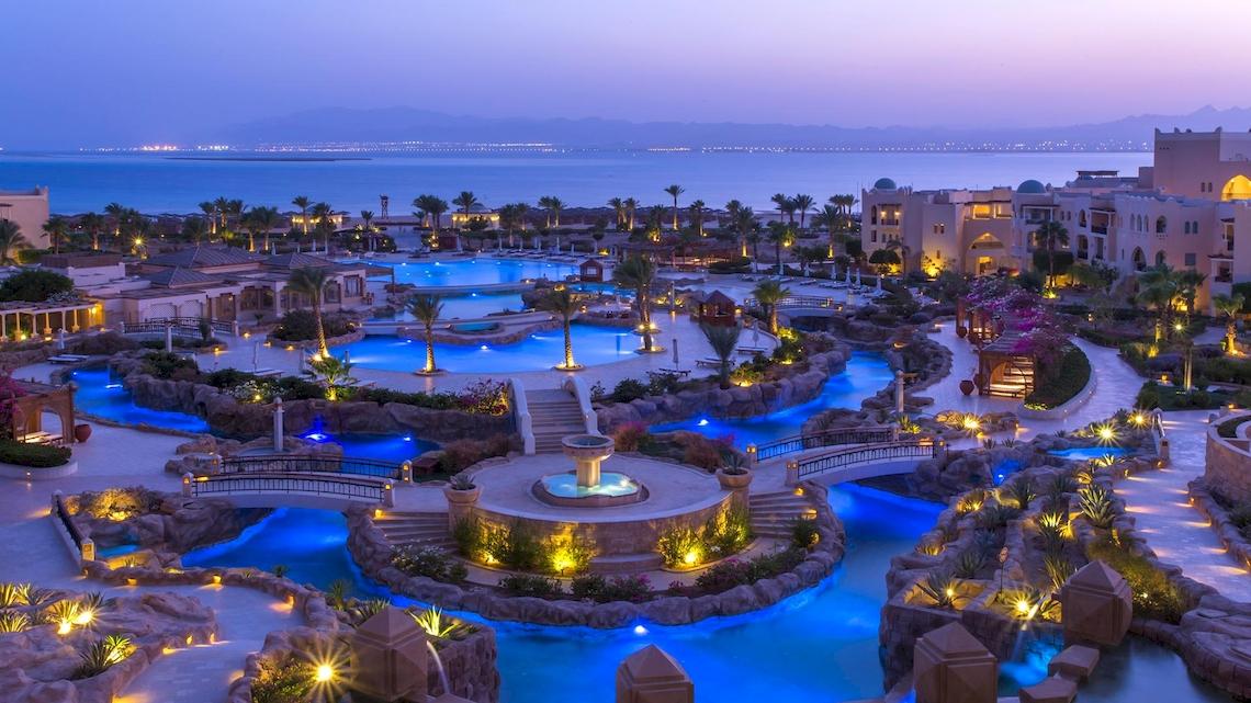 Abendansicht des Kempinski Hotels Soma Bay mit illuminierten Swimmingpools und Blick auf das Meer.