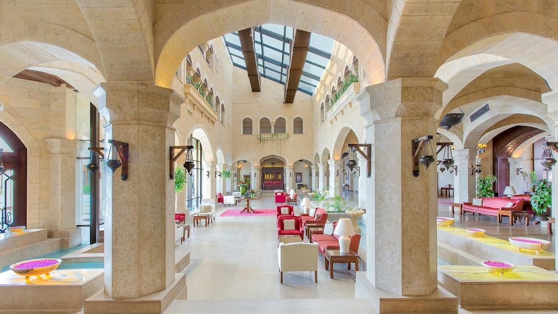 Die geräumige und helle Halle des Kempinski Hotel Soma Bay mit Säulen, Sitzgelegenheiten und Pflanzen.