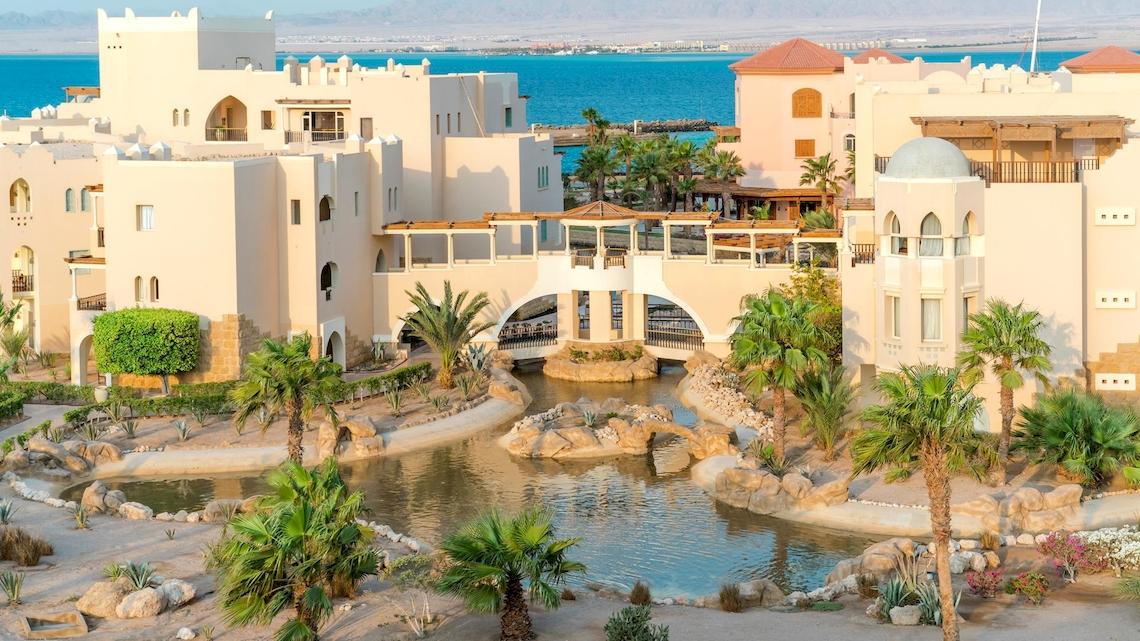 Außenansicht des Kempinski Hotels Soma Bay mit Blick auf den Ozean, Brücke und Palmen