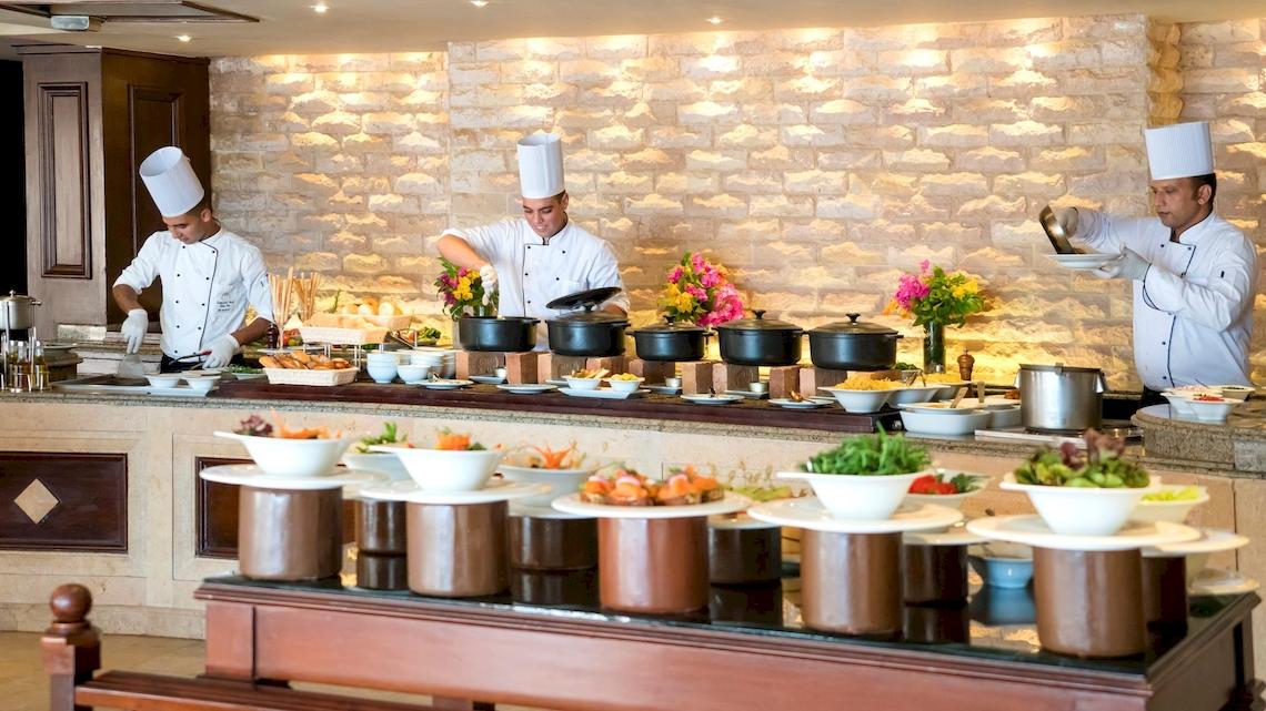 Ein Buffet im Kempinski Hotel Soma Bay mit Köchen, die Speisen zubereiten.