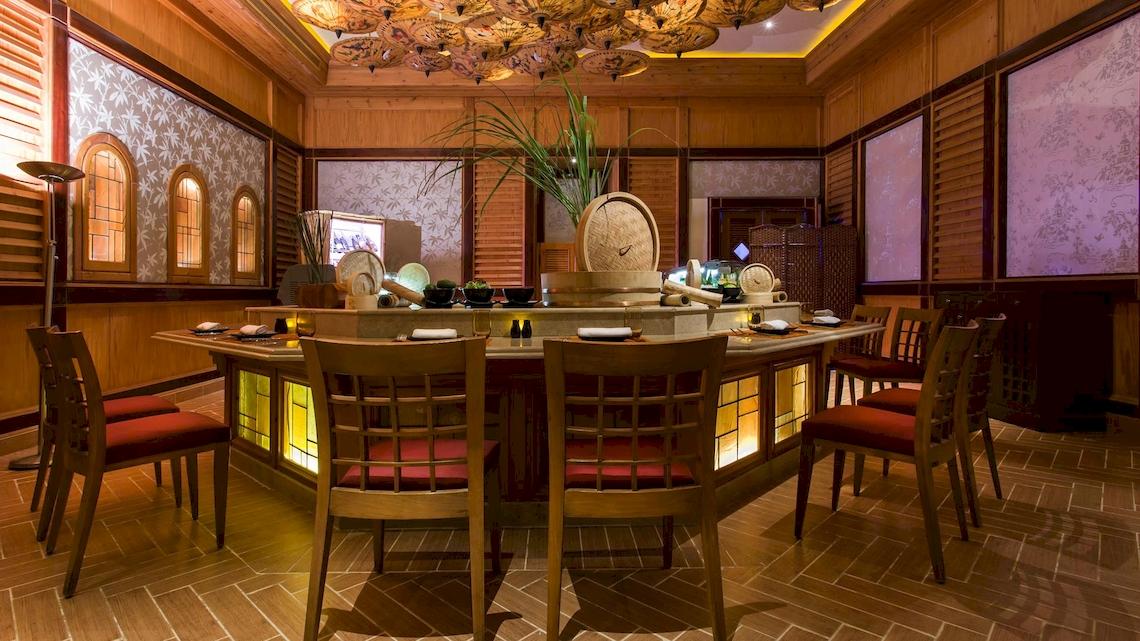 Innenbereich des Kempinski Hotel Soma Bay mit einem Tisch und Stühlen, umgeben von Holzelementen und beleuchteten Wänden.